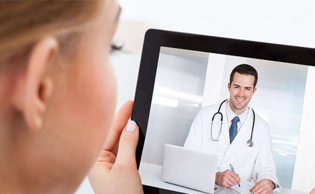Picture of a happy woman having a video conference with her fertility doctor in Costa Rica.  The woman is holding a tablet and is talking to her doctor during a conference call.